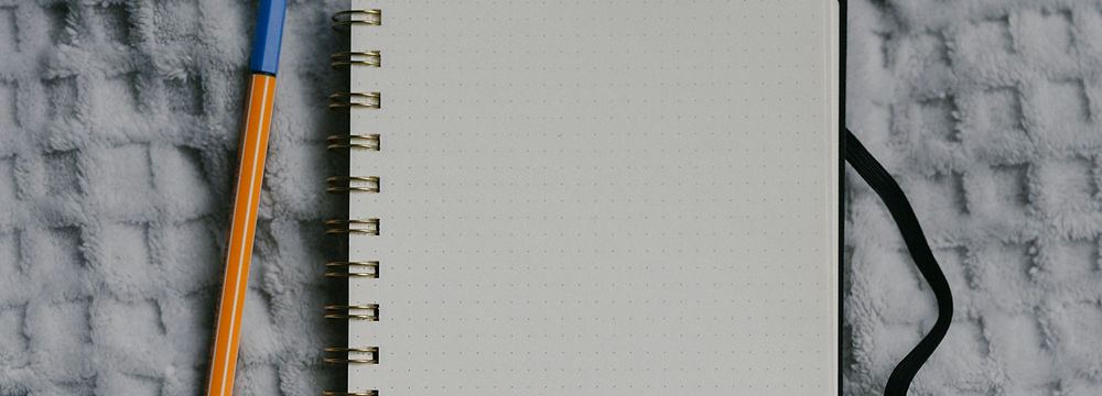 An open notebook and pen resting on a cozy blanket.