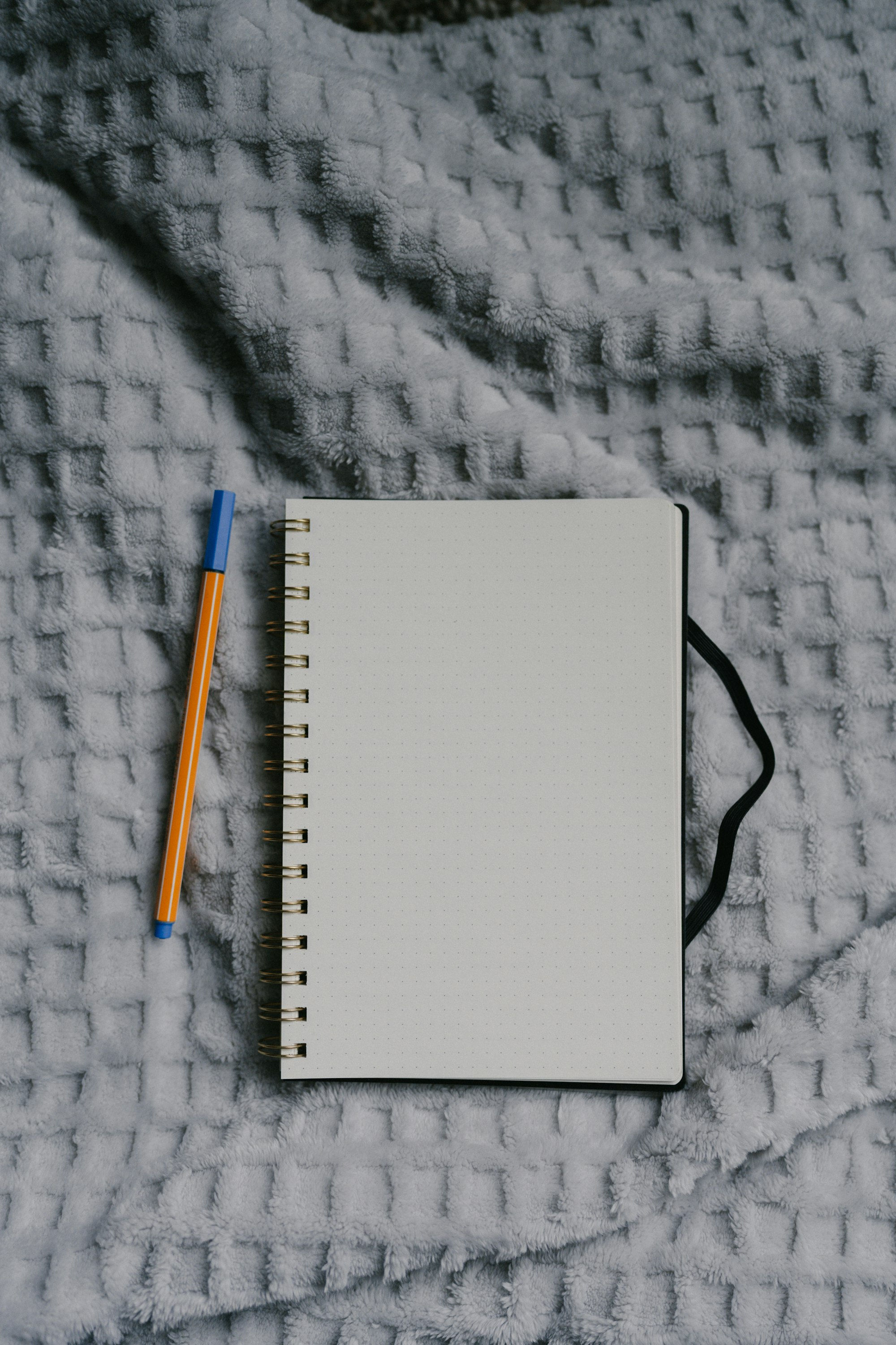 An open notebook and pen resting on a cozy blanket.