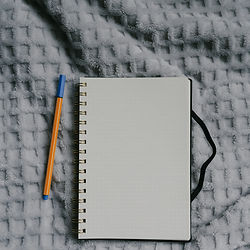 An open notebook and pen resting on a cozy blanket.