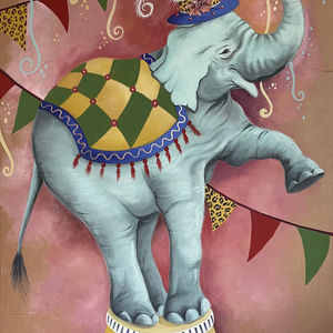 Circus elephant with a feather hat, balancing on a drum.