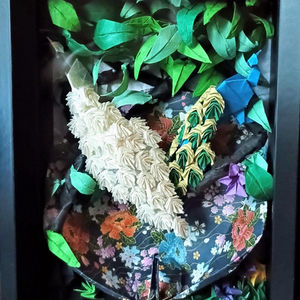 Hand-folded origami peacocks displayed in a fine-art shadow box by Safety Harbor paper folding artist Cindy Huang Engle, showcasing intricate feather detail sculpted entirely from folded paper.
