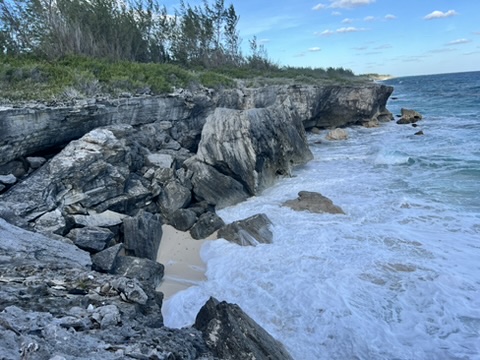 Rocky beach with waves washing up on the Atlantic Ocean side of Eleuthera, Bahamas, showcasing the rugged coastline and clear blue waters.
