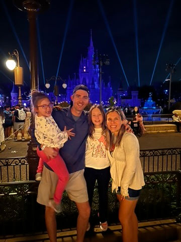 Family in reserved Magic Kingdom fireworks viewing area with Cinderella Castle lit up at night