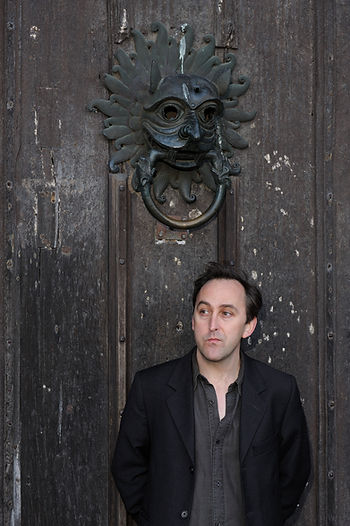 Richard Sugg stands in front of a large door with an ornate knocker