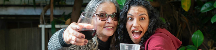 Two happy women hold up their drinks.Photo by Kampus Production