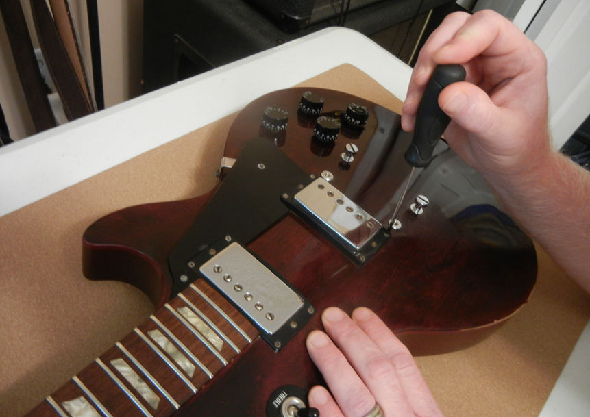 Checking pickup mounts on a guitar.