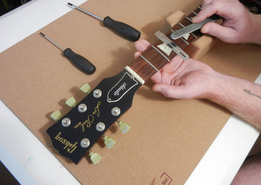 Polishing frets on a guitar.