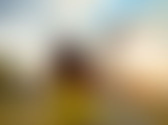 African American woman in a yellow shirt stretching her arms out to the sky.