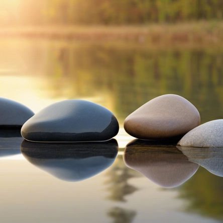Smooth stones on a calm lake at sunset, creating peaceful ripples. The serene background is a soft blur of trees and golden light.