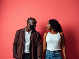 Black woman and black man holding hands and staring at one another.