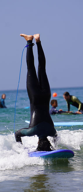 Lizensierter Surfcoach Abdullah im Handstand auf dem Surfbrett im Meer während der Surfstunde - Spaß muss sein!