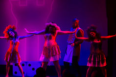 a group of people are dancing in front of purple lights