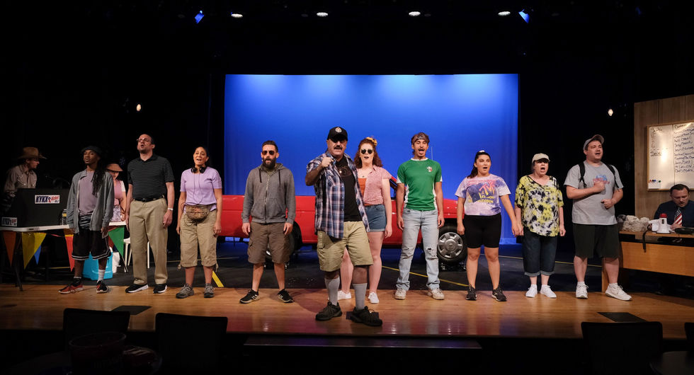 a group of people standing on a stage in front of a red truck