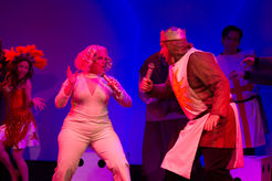 a woman singing into a microphone next to a man in a knight costume