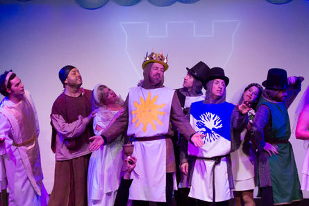 a group of people dressed in medieval costumes including a man in a crown