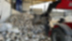 Large pile of e-waste at a recycling facility. The facility has a partially enclosed area with metal walls and a roof.