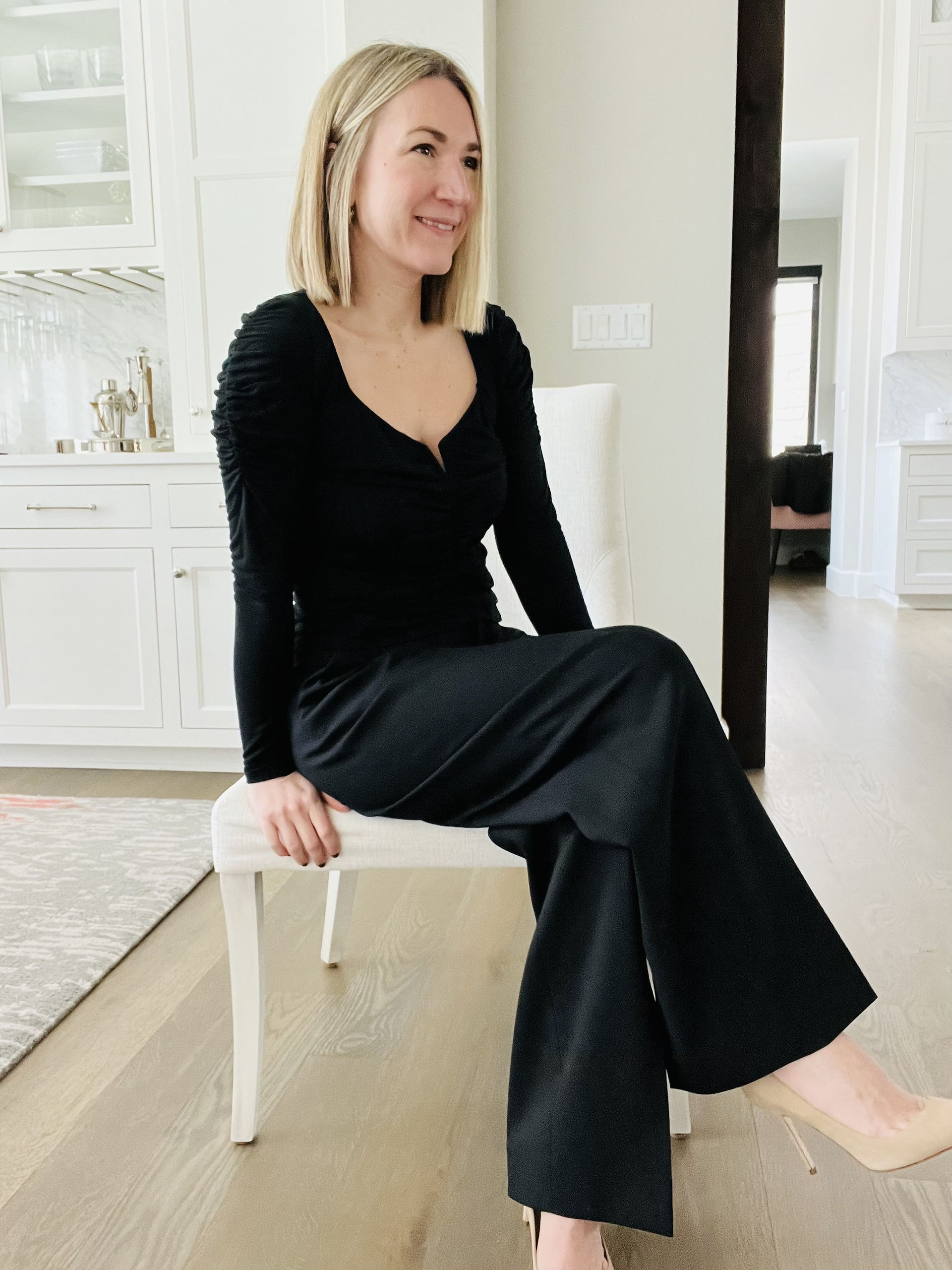 Natalie, top Austin stylist sitting in all black look with beige pumps