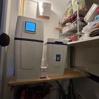 Z8-Water waterontharder met los zoutvat geplaatst op een houten draagplank in de trapkast onder een opbergstelling
