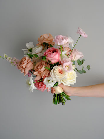 Wedding bouquet with pink and white florals held by a woman.
