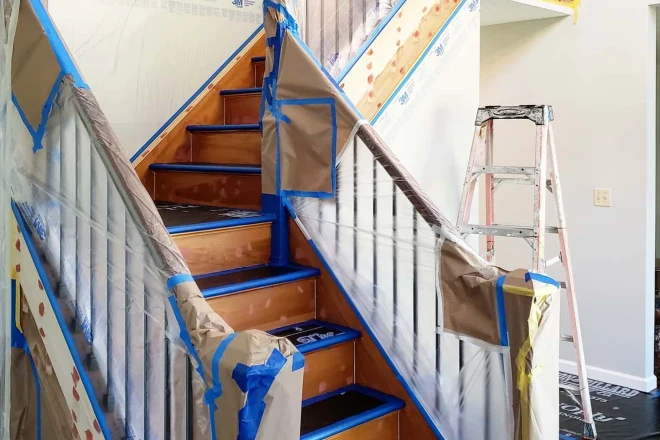 7 Factors that Affect the Cost of Interior Painting 4 A staircase covered with plastic and painter's tape in preparation for a new coat of paint