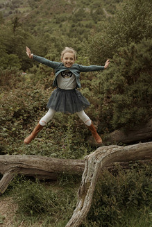 child jumping freely during outdoor family photography session in Cumbria