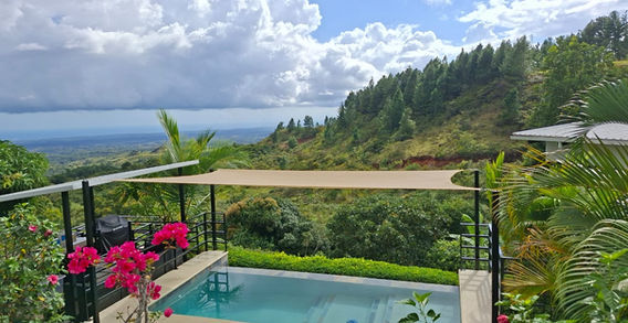 Elegant infinity pool at Finca Colibrí Panama overlooking lush mountains and the distant ocean under a clear blue sky