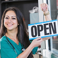Smiling clinician hanging an open sign in a medical clinic