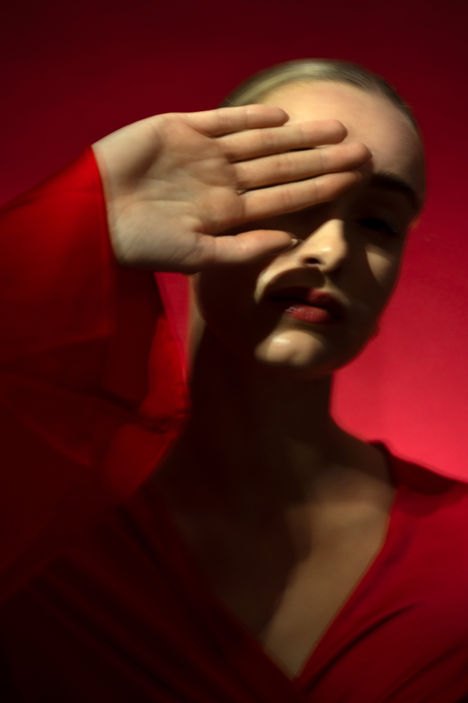 Portretfotografie: studioportret van vrouw in spotlicht in rode tinten door portretfotograaf Ellen Meijer 