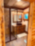 Eye-level view of a modern walk in shower with natural stone tiles and large window overlooking Northern Michigan forest