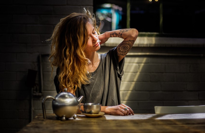 Person holding a cup of coffee that reads "Busy Introverting"