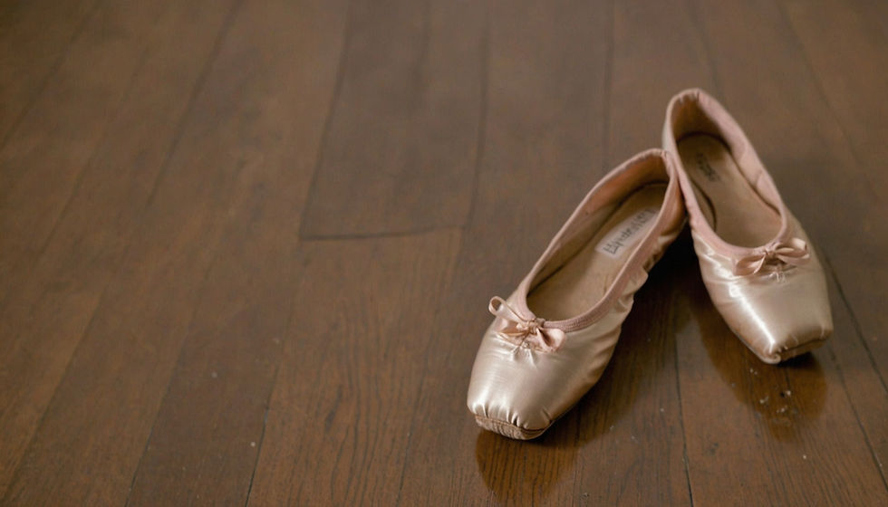 Ballet dancer’s feet in pink pointe shoes standing en pointe on a glossy floor under soft teal and pink light