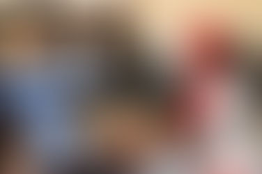 cabin attendant helping passenger stow carry-on bag in overhead bin