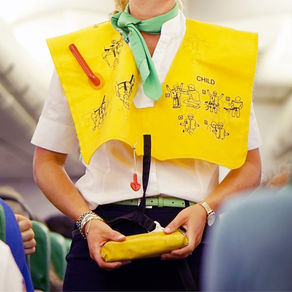 cabin attendant wearing life jacket in pre-takeoff safety demonstration