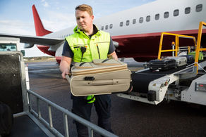ground crew unloading checked baggage from a plane