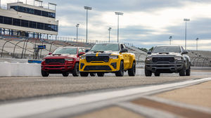 2027 Ram 1500 Rumble Bee Muscle Trucks with wide stance, front splitter, and rear spoiler on a racetrack