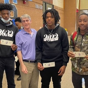 a teacher and students stand shoulder-to-shoulder displaying money