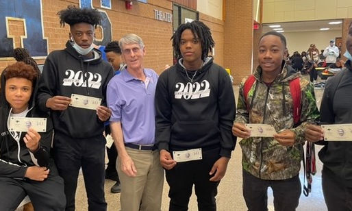 a teacher and students stand shoulder-to-shoulder displaying money