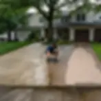 Worker comparing concrete and paver driveway cleaning results in Elkton townhomes
