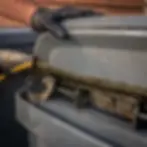 Close-up of hand scrubbing grimy trash can lid hinge in Elkton