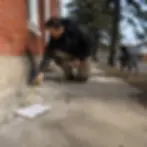 Worker measures cracked concrete walkway during estimate visit in Elkton