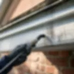 Close-up of gloved hand treating black streaked gutter in Elkton