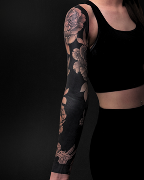 Front angle of a blackout floral arm sleeve tattoo with bold blackwork and floral elements.