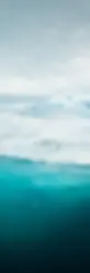 Das Bild zeigt eine eisige Landschaft mit Schnee und Gletschern im Hintergrund. Im Vordergrund ist kristallklares, blaues Wasser zu sehen, das in starkem Kontrast zu den weißen Eismassen steht. Bild von Alexander Hafemann