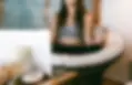 Das Bild zeigt eine Frau in einer Meditationshaltung. Im Vordergrund ist ein Laptop zu sehen.