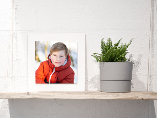 Ein Bild eines Jungen in einem Passepartout 8Fotoprodukt) auf einem Holzregal.