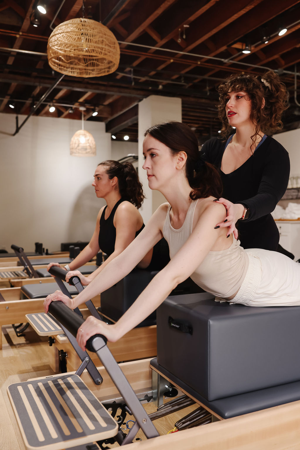 Reformer Pilates instructor adjusting client's form