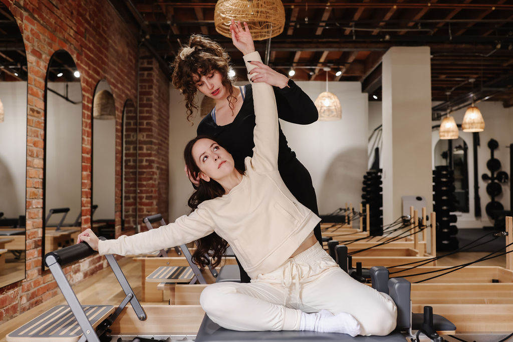 Instructor guiding a client through a stretch on the Reformer