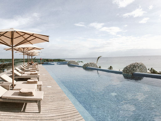 infinity pool in mexico with lounge chairs and umbrellas overlooking the ocean