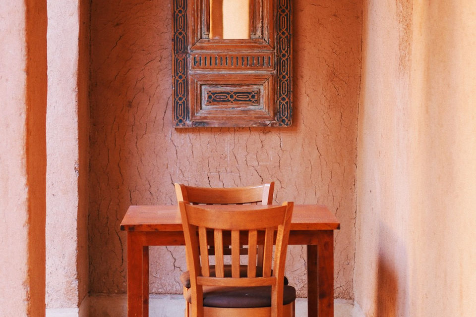 Chaise et table en bois contre un mur ocre dans un riad