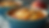 Blue dish with peach cobbler, featuring golden crust and peach chunks. A spoon rests inside. Warm, inviting setting with peach in background.